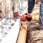 Plumber fixing orange pipes during a new construction of a house